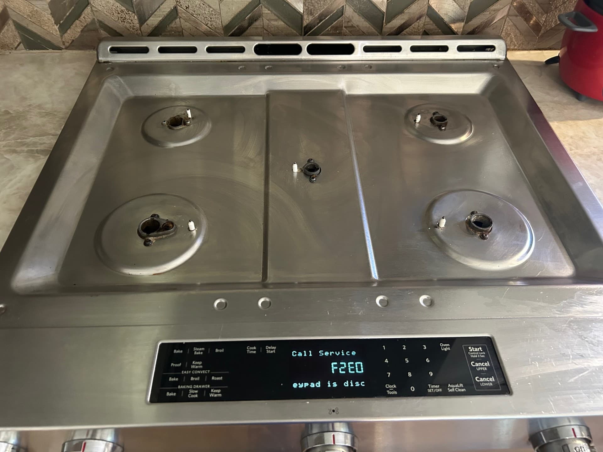 Stainless steel stove with grates removed, displaying an F2E0 error code on the panel.