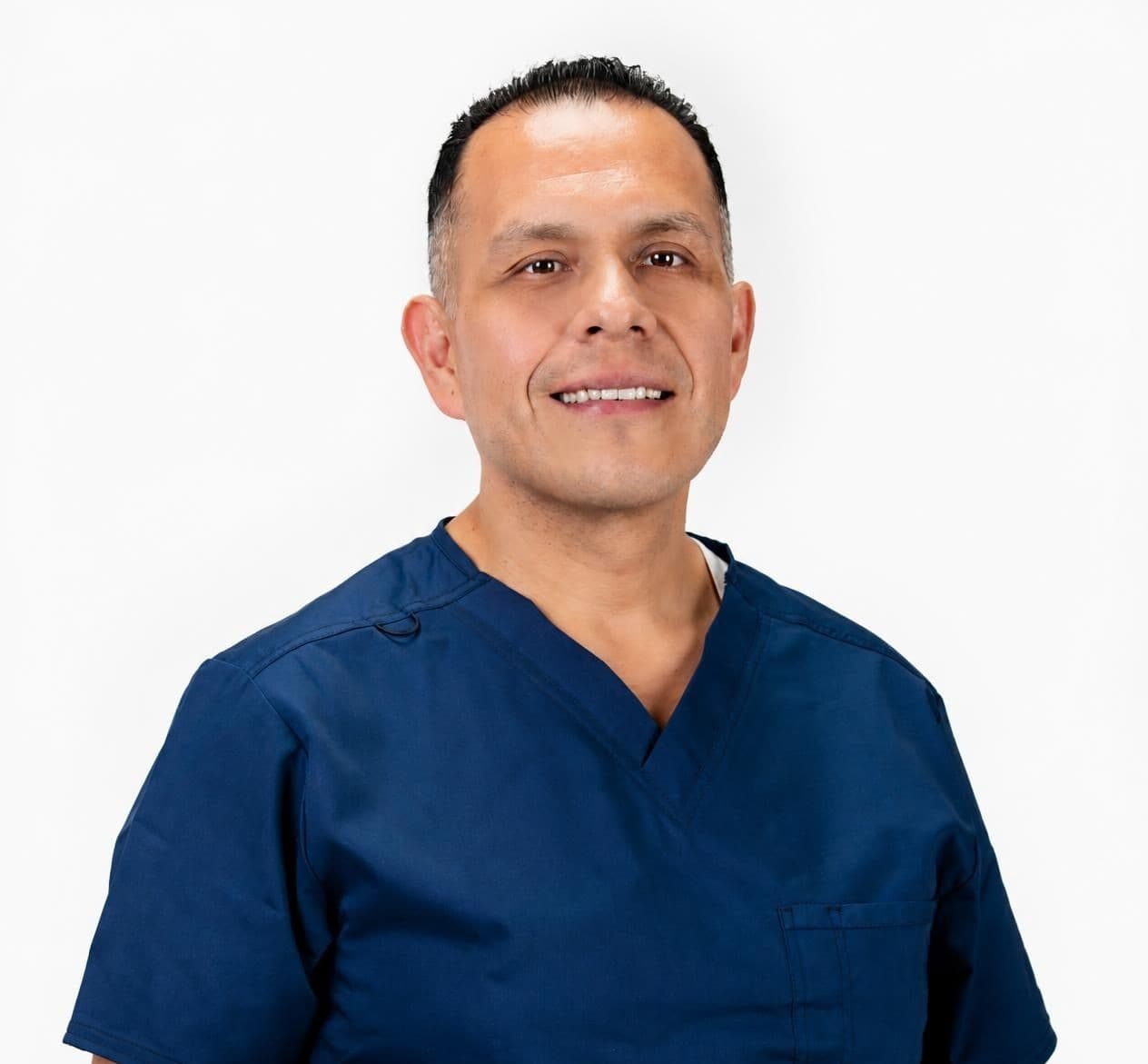 Smiling male healthcare professional in blue scrubs, head and shoulders portrait against a white background.