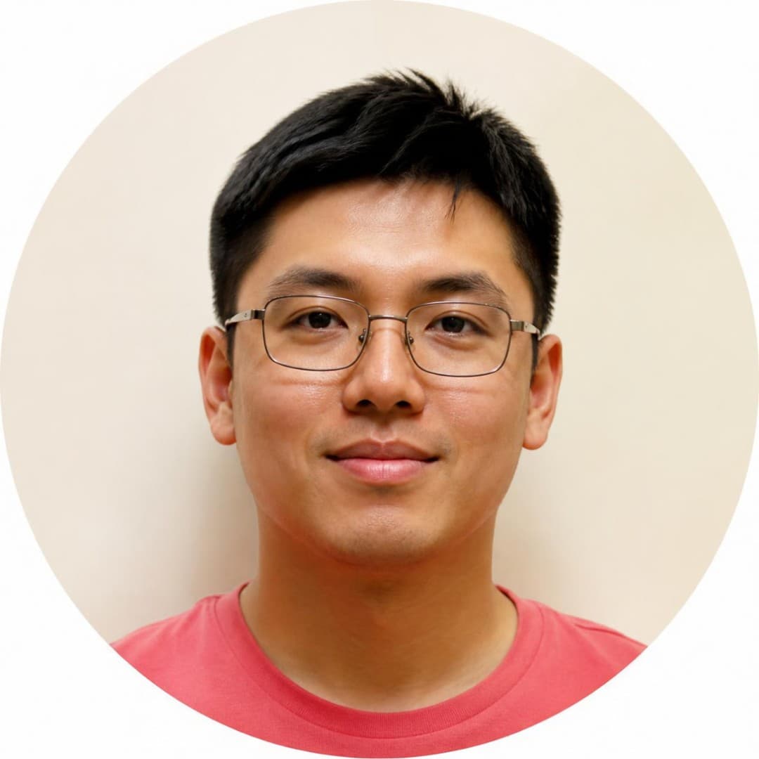 Circular headshot of a smiling man with short black hair, glasses, and a red shirt.