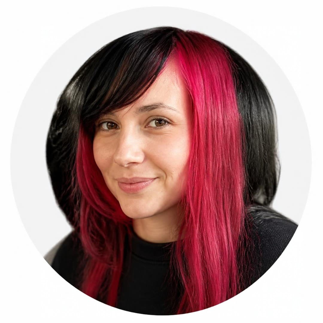 Woman with long black and bright pink hair smiling in a circular headshot portrait.